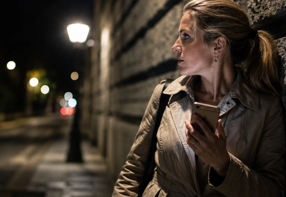 Lone worker holding a phone while feeling unsafe during an evening street visit