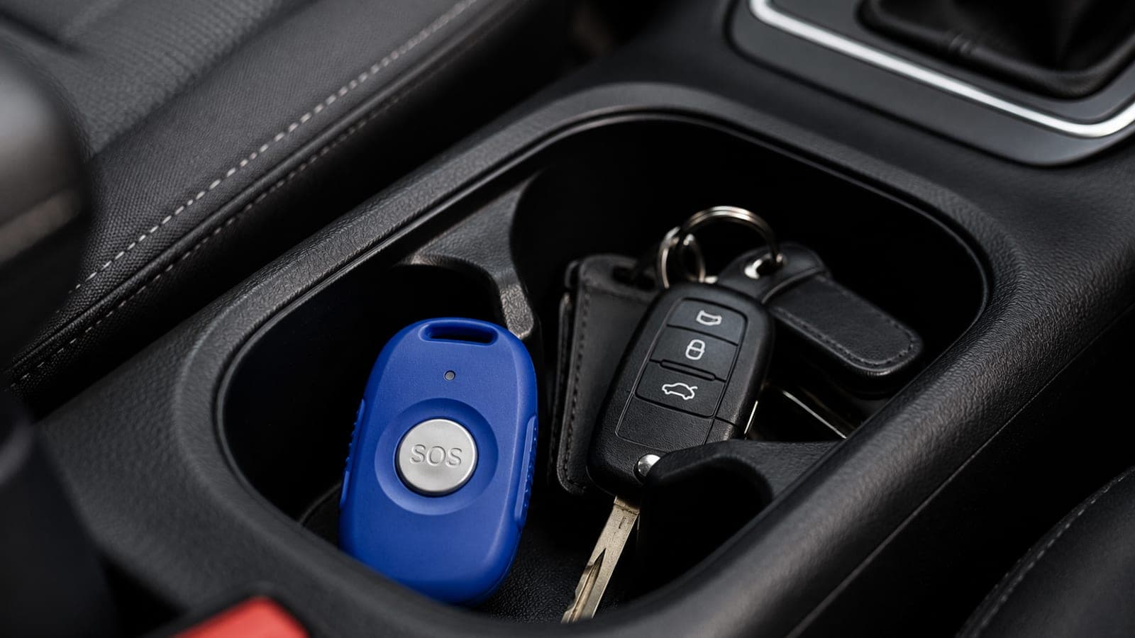 Blue SOS fob beside car keys in a vehicle cup holder representing device carrying routines